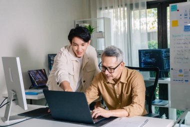Bir acemi birliği kampı eğitimi sırasında akış çizelgelerini analiz eden bir grup Asyalı kıdemli yazılım geliştirici.