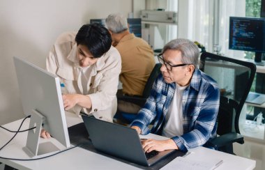 Bir acemi birliği kampı eğitimi sırasında akış çizelgelerini analiz eden bir grup Asyalı kıdemli yazılım geliştirici.