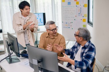 Kıdemli geliştirici ekibi modern bir bilgisayar çalışma istasyonunda yazılım işbirliği ve kodlamada başarıyı kutluyor