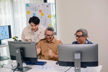 Kıdemli geliştirici ekibi modern bir bilgisayar çalışma istasyonunda yazılım işbirliği ve kodlamada başarıyı kutluyor