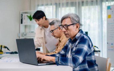 Bir acemi birliği kampı eğitimi sırasında akış çizelgelerini analiz eden bir grup Asyalı kıdemli yazılım geliştirici.