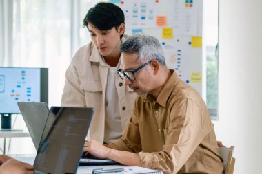 Bir acemi birliği kampı eğitimi sırasında akış çizelgelerini analiz eden bir grup Asyalı kıdemli yazılım geliştirici.