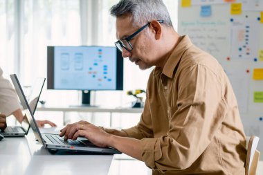 Bir acemi birliği kampı eğitimi sırasında akış çizelgelerini analiz eden bir grup Asyalı kıdemli yazılım geliştirici.