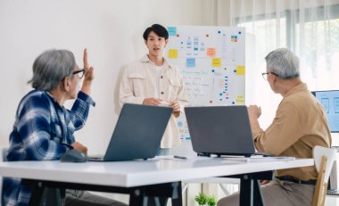 Kıdemli programcı bot kampı, Asyalı genç eğitmen kıdemli öğrencilere beyaz tahtadaki bir programlama, algoritma düşünme ve basit kod alıştırmaları yoluyla rehberlik ediyor.