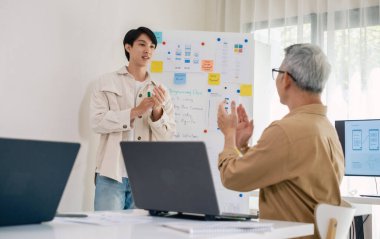 Kıdemli programcı bot kampı, Asyalı genç eğitmen kıdemli öğrencilere beyaz tahtadaki bir programlama, algoritma düşünme ve basit kod alıştırmaları yoluyla rehberlik ediyor.