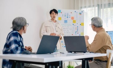 Kıdemli programcı bot kampı, Asyalı genç eğitmen kıdemli öğrencilere beyaz tahtadaki bir programlama, algoritma düşünme ve basit kod alıştırmaları yoluyla rehberlik ediyor.