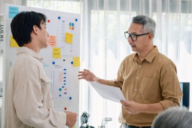 Kıdemli programcı bot kampı, Asyalı genç eğitmen kıdemli öğrencilere beyaz tahtadaki bir programlama, algoritma düşünme ve basit kod alıştırmaları yoluyla rehberlik ediyor.