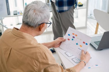 Ofiste akış şeması ve sistem süreci belgeleriyle yazılım geliştirmeyi planlayan kıdemli programcı