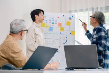 Kıdemli programcı bot kampı, Asyalı genç eğitmen kıdemli öğrencilere beyaz tahtadaki bir programlama, algoritma düşünme ve basit kod alıştırmaları yoluyla rehberlik ediyor.