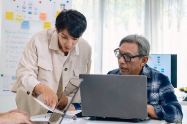 Bir acemi birliği kampı eğitimi sırasında akış çizelgelerini analiz eden bir grup Asyalı kıdemli yazılım geliştirici.