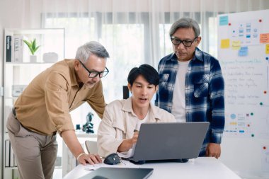 Bir acemi birliği kampı eğitimi sırasında akış çizelgelerini analiz eden bir grup Asyalı kıdemli yazılım geliştirici.