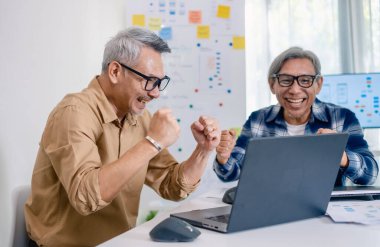 Kıdemli geliştirici ekibi modern bir bilgisayar çalışma istasyonunda yazılım işbirliği ve kodlamada başarıyı kutluyor