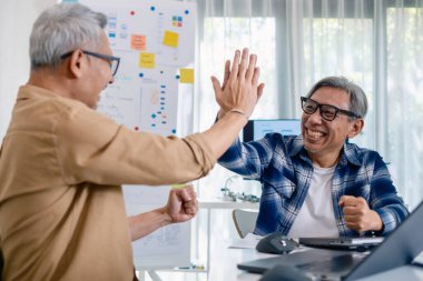 Kıdemli geliştirici ekibi modern bir bilgisayar çalışma istasyonunda yazılım işbirliği ve kodlamada başarıyı kutluyor