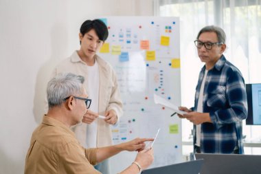 Kıdemli programcı bot kampı, Asyalı genç eğitmen kıdemli öğrencilere beyaz tahtadaki bir programlama, algoritma düşünme ve basit kod alıştırmaları yoluyla rehberlik ediyor.