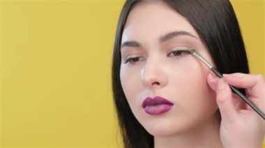 Kızlar kaş eyeliner uygulayarak visagist, yakın çekim. Makyaj sanatçısı modelleri göz için göz farı uygulamak. Güzel Asyalı kadın makyaj visagist aşağı bakıyor