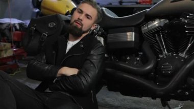 Erkek motorcu motosiklet yakın katta oturuyor. Motosiklet motoru tarafından sırtını yaslanmış siyah deri ceketli genç adam. Onun el ele tutuşarak sakallı beyaz adam göğüs üzerinde çarpı işareti