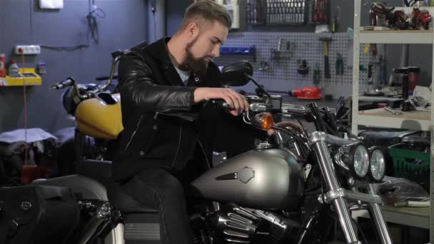 Jonge Mannelijke Biker Poseren Klassieke Bijl Motorfiets Workshop Cool Bebaarde — Stockvideo