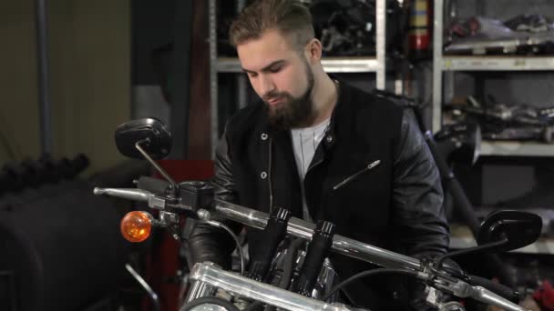 Junge Männliche Biker Begutachten Den Chopper Der Motorradwerkstatt Bärtiger Kaukasier — Stockvideo