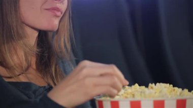 Orta yaşlı kadın sinema Kova patlamış mısır gevreği alarak. Beyaz kadın patlamış mısır yeme yavaşça kapatın. Tam Kova patlamış mısır onun elinde tutan Brownhaired kadın