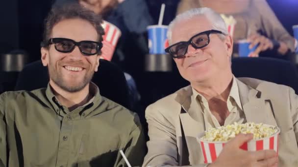 电影在电影院里的两个成年男性 老人和中间岁男人笑着从那部电影 白发苍苍的老人在电影院吃爆米花 — 图库视频影像