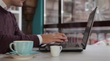 Beyaz adam kafede kahve için süt ekleyerek. Laptop ile kafede oturan genç adam. Onun sabah kafede harcama adam