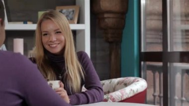 Çekici genç kadın sevgilisi kafede söyledikleri gülüyor. Genç Kafkas kadın beyaz fincan çay içme. Sarışın kız erkek arkadaşını gülümseyen