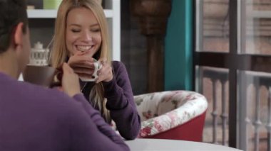 Genç çift kafede bir randevusu var. İki kahve yudumlarken masada konuşuyor. Sarışın kız erkek arkadaşına onu önünde hangi oturma seyir