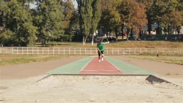 Молодой Самец Тренировался Прыгать Длину Стадионе Спортсмен Приземляется Ноги После — стоковое видео