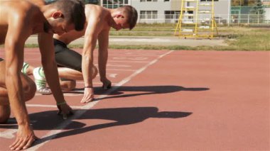 Stadyumda koşmaya başlayan iki genç athlets. İki yakın beyaz sportmen olarak pozisyon sıçramak önce ayarlayın. Altıncı ve yedinci pist çalışan başlayan iki taslakları