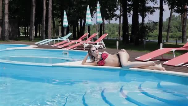 Long Shot Beautiful Woman Sunglasses Red Swimsuit Lying Pool Edge — Stock Video