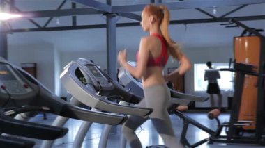 Fitness merkezinde koşu bandı üzerinde çalışan ince beyaz kadın. Kızıl saçlıya kız onun dayanıklılık koşu bandı üzerinde eğitim. Koşu bandı üzerinde çalışan tarafından çekici ince kadın kayıp callories