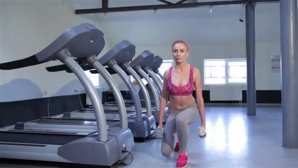 有吸引力的红发女孩在健身中心锻炼升压 漂亮白种女人训练臀大肌在健身房里 年轻人适合交替做大步骤由不同的双腿的女人 — 图库视频影像