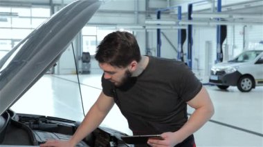 Sakallı mekanik kayıt araba sorunları tablet vasıl araba servisi için kapatın. Esmer beyaz adam onun siyah tablet için veri girme. Otomotiv uzman tablet araba tanılama kullanma