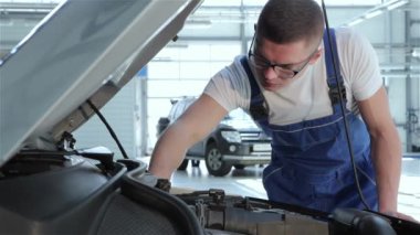 Sarışın tamirci arabanın serviceabillity kadar kontrol. Araba motor parçaları dokunmadan genç bir beyaz adam. Otomotiv uzman araba servisinde motor bölmesi üzerinde bükme
