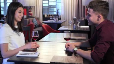 Genç çift restoranda kızartma. Çekici insanlar romantik Tarih kafede sahip yan görünüm. Esmer erkek ve kadın onların bardak kırmızı şarap kaldırma