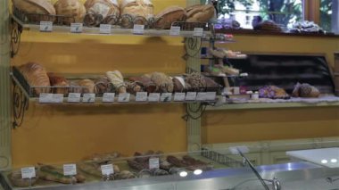 Güzel kadın satıcı pastanede dükkan tezgahına ellerini koyarak. Dükkan tezgahına yaslanmış kahverengi saçlı genç bir kadın. Çekici beyaz kadın arka plan karşı duran