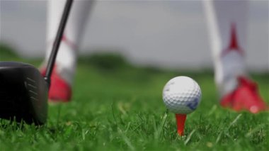 Mikro bir tee atış yapma golf oyuncusu kapatın. Golf topu golf kulübü tarafından swiping kırmızı spor ayakkabı. Kaç ışık yapma golf oyuncu isabet önce sallanır