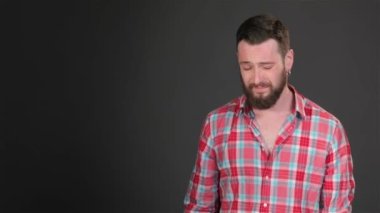 Sakallı adam onun boyun arkasında tırmalamak. Yakışıklı hippi, boynunda elini tutarak. Beyaz esmer adam koyu gri arka plan üzerinde aşağı bakıyor