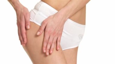 Onun uyluk masaj eller yakın çekim. Kafkas kadın lezzetli bacağını dokunmadan. Genç kadın beyaz arka plan üzerinde izole onun kalça okşama