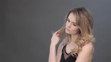 Kameraya glowering oldukça beyaz kız. Seksi kadın modeli crossly onun saç atma. Çekici kadın mutsuz olarak izole koyu gri arka planı arıyorum