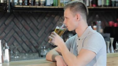 Beyaz adam barda tost topluyor. Attracrive adam dirsek tarafından bar sayacı naya yaslandı. Sarışın adam kameraya bir bardak bira uzamış