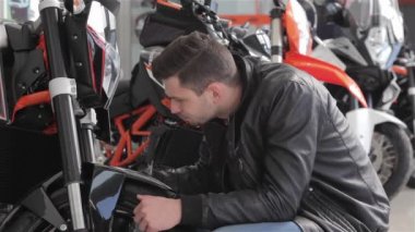 Yeni siyah motosiklete bakan bir adamın yakını. Motokros bisikletinin ön çatalını inceleyen beyaz adam. Gülümseyen satıcı motosiklet onaylayarak kadar başparmağını kaldırma