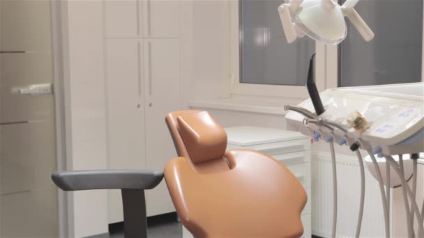 若い歯科医は 歯科医の椅子に ひげを生やした医者歯医者の椅子近く座って 男性の歯科専門歯科医の椅子の背もたれに寄りかかって — ストック動画
