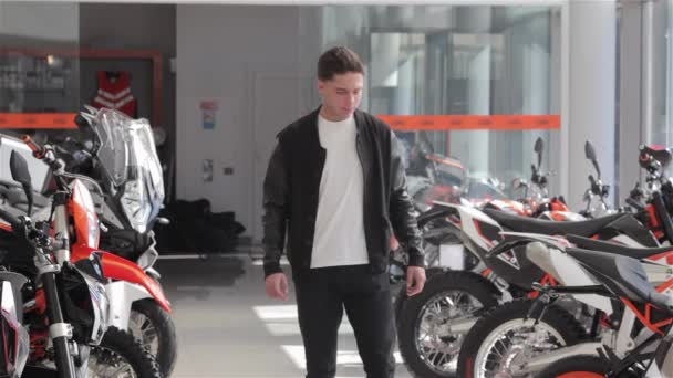 Νεαρός Καυκάσιος Άνδρας Που Επιλέγει Μοτοσικλέτα Στο Σαλόνι Μοτοσικλέτας Μπρουνέτ — Αρχείο Βίντεο