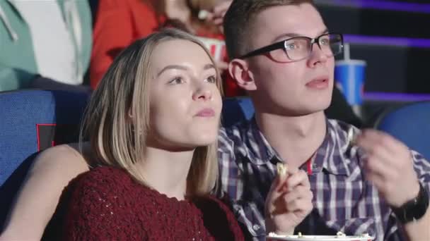 在晚上时段的年轻夫妇 在电影院看电影的朋友们 电影院 娱乐和人们的观念 快乐的朋友 看电影的影院 夫妇和其他人吃爆米花和 — 图库视频影像