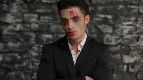男性の吸血鬼は時計を見て怒る レンガの壁の黒い背景にポーズ吸血鬼のイメージの男 ハロウィーンのコンセプトと衣装 — ストック動画
