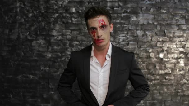 男性吸血鬼擦去他嘴里的血 人的形象 吸血鬼在砖墙的黑色背景摆姿势 万圣节概念和服装 — 图库视频影像