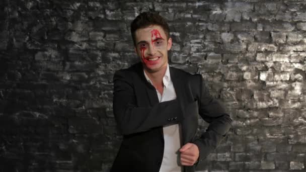 ヴァンパイアの男が名刺を出すコピースペース レンガの壁の黒い背景にポーズ吸血鬼のイメージの男 ハロウィーンのコンセプトと衣装 — ストック動画