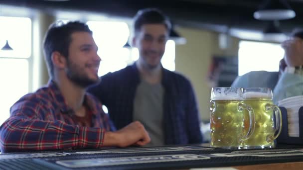 朋友见面后劳累了一天 三个开朗朋友碰杯啤酒在酒吧 喝一杯啤酒 友谊和学士方概念 快乐的男性朋友喝啤酒在酒吧或酒馆 — 图库视频影像