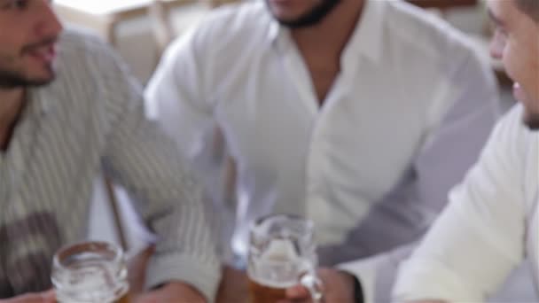 カジュアルの つの幸せな若い男性のクローズ アップを着用するビールのパブで一緒に座りながらビールで乾杯します レジャー 友情と 独身パーティー コンセプト 幸せの男性の友人でビールを飲む — ストック動画